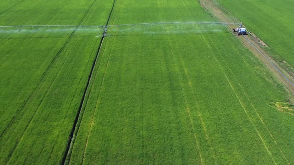 Aerial view of circular irrigation watering agricultural equipment on a young green field of wheat