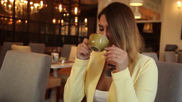 Business Woman in Business Clothes Drinking Tea with Cafe Sitting at the Table Having a Good Mood