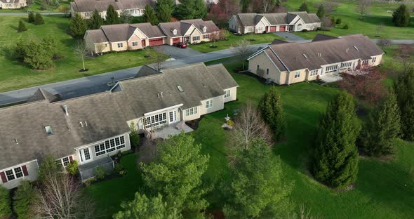 Rear of condo apartment duplex houses. Rising aerial reveals homes in spring. Green nature grass and