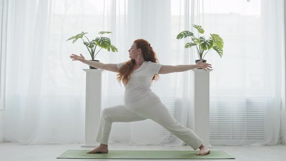 Pregnant Woman Doing Yoga Standing in Warrior Position Indoors in Slow Motion.