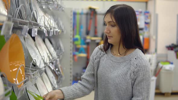 Young Woman in a Household Goods Store Chooses Plates