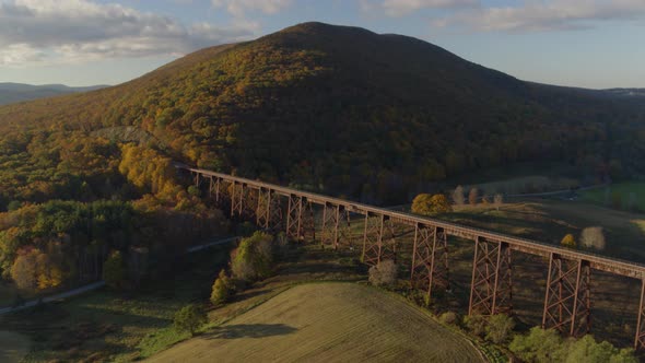 Aerial of railroad bridge passing over valley landscape on a sunny day