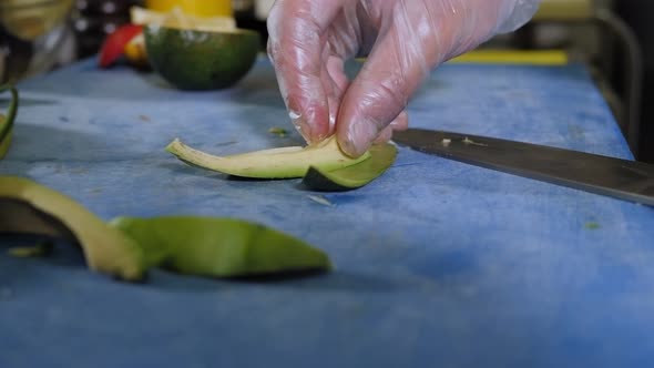 Closeup of a Chef Cutting Avocado with a Knife on a Cutting Board in Restaurant