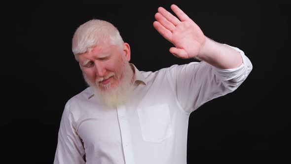 Man with Albinism Raises His Hand to Protect His Eyes From Bright Light and Puts on His Sunglasses
