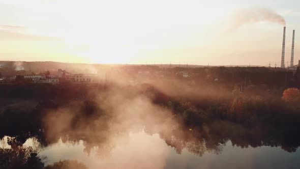 smoke from the fire are spreading over the river at sunset on the background of a power station