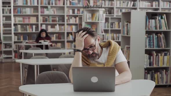Mature Stressed Tired Man in Library Wear Glasses Feel Pain Tired of Computer Screen Studying Work