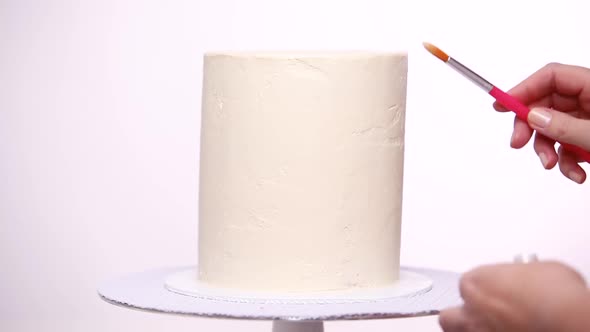 Time lapse. Step by step. Applying glitter dust on tall birthday cake with white buttercream icing.