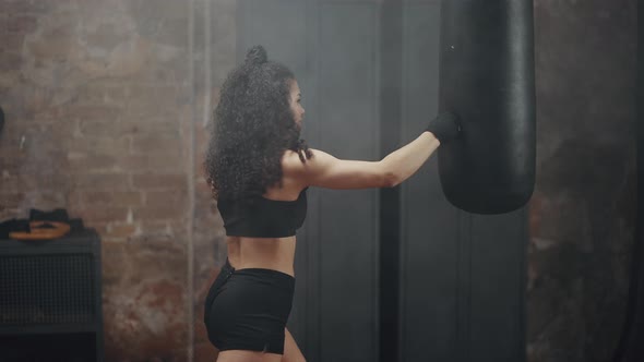 Woman with Kinky Hair Kicks Punching Bag at Boxing Classes