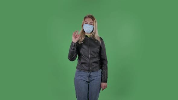 Portrait of Beautiful Young Woman in Medical Mask Is Looking Straight Sighs Relieved and Making Sign