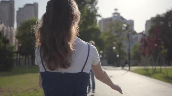 Little Boy Running Toward His Older Sister and Hugging Her in the Summer Park