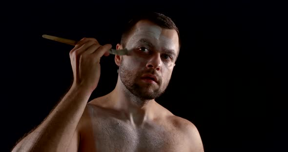 Male Actor Is Covering His Face By White Greasepaint Using Brush in Dark Room