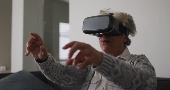 African american senior woman gesturing while wearing vr headset at home
