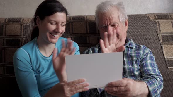 Woman And Elderly Man Communicate Video Call Over Internet Greeting Waving Hand