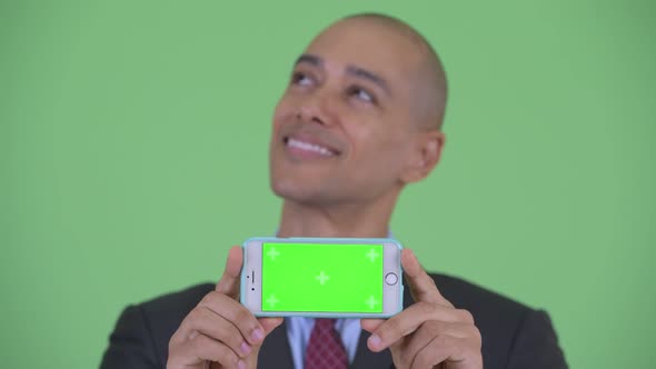 Face of Happy Bald Multi Ethnic Businessman Thinkin While Showing Phone