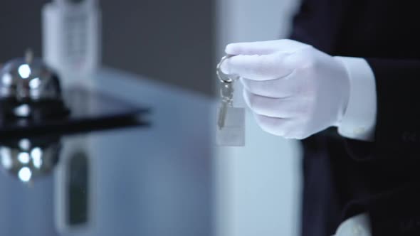 Hotel Administrator Hand in Glove Giving Lady Key on Chain