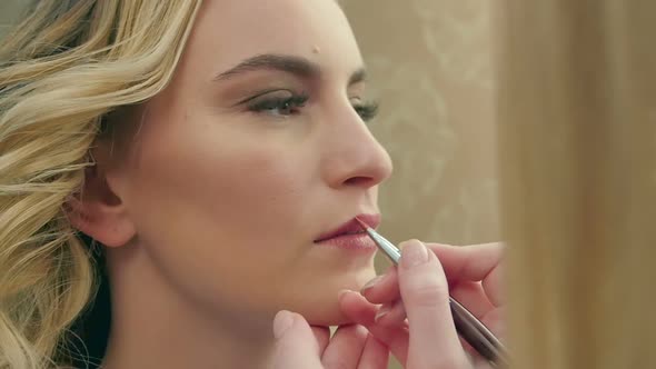 Professional Makeup Artist Applying Brown Lipstick on Lips of Model