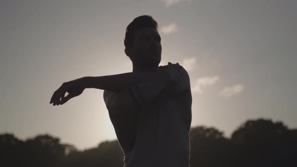 Man Stretches Before He Works Out Whilst Being Silhouetted By The Evening Sun In Slow Motion  - Ungr