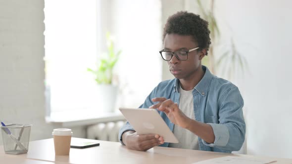 Young African Man Using Tablet While Sitting in Office