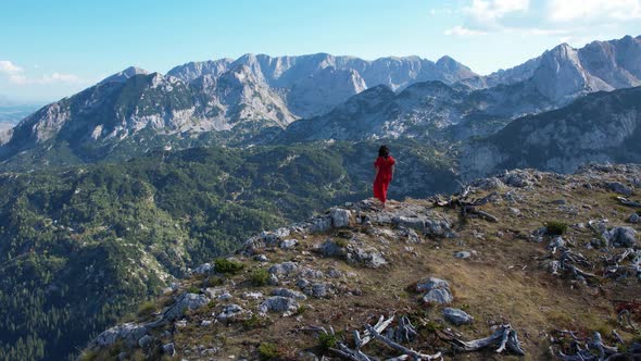 Drone View to Woman in Red Dress on Mountain Top