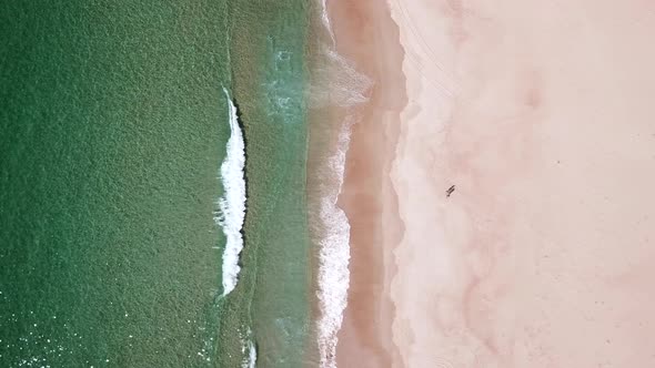 Over Head Drone Shot Of Two People On White Sand Beach With Waves Rolling In, Tasmania Australia