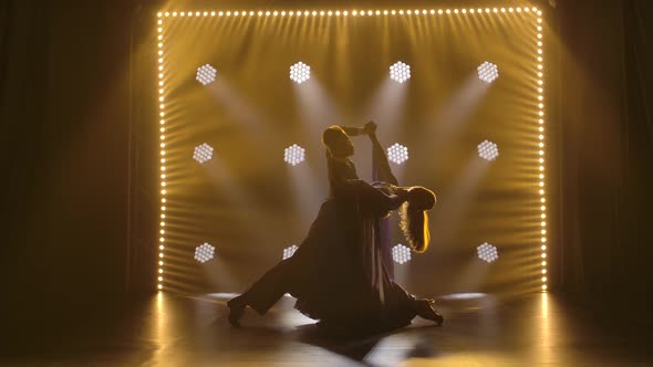 A Pair of Professional Ballroom Dancers Dancing a Waltz in a Dark Studio in the Spotlight. Slow