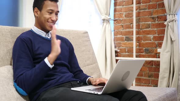 African Man Doing Video Chat on Laptop Sitting on Sofa at Home