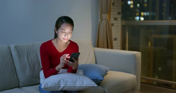 Woman use of mobile phone at home in the evening