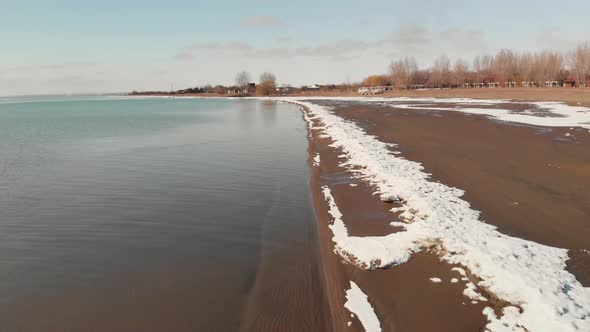 Aerial View of Beach with Snow at Lake