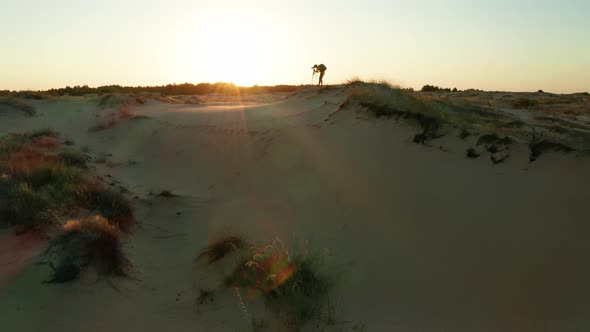 Photographer on a Sand Dune in the Desert at Sunset