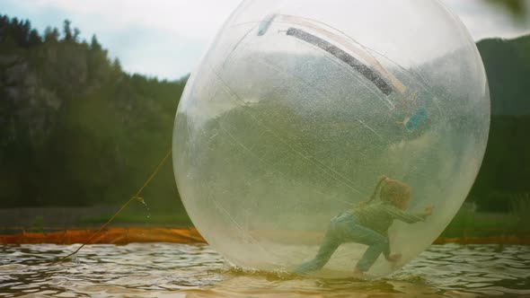 Preschooler Girl Rides Water Sphere Floating in Small Pool