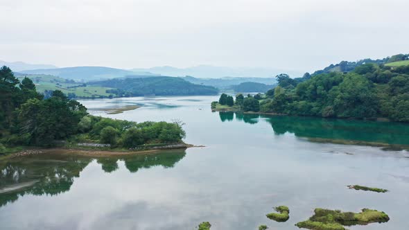 Cinematic aerial view of calm turquoise water lake in forest environment