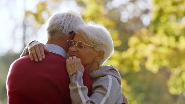 Elderly Caucasian Couple Hugging Woman Moves Her Hand Across Her Husband's Back Selective Focus Copy