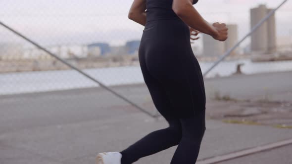 Young Woman In Black Sportswear Jogging Along Harbour