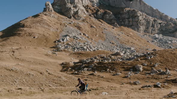 Background of Mountain Man Rides Bicycle with Child in Chair Rbbro