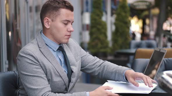 Business Man Working with Papers in Outdoor Cafe