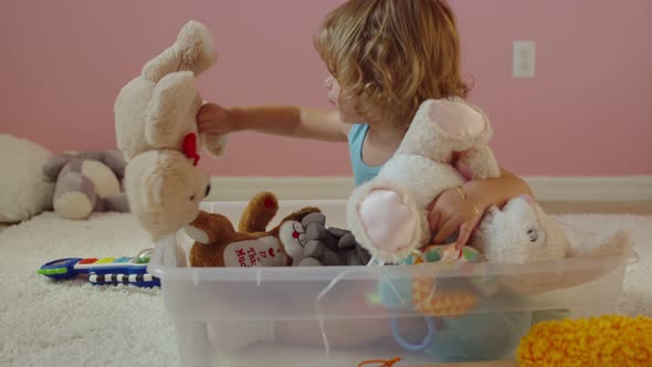 Little Girl Playing with Stuffed Animals While Sitting Inside Plastic Bin 