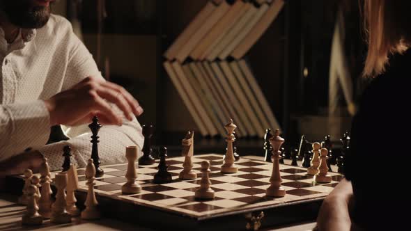 Young Adult Man and Woman Playing Chess Indoors