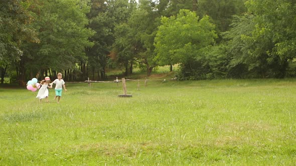 Little Boy Holds the Girl By the Hand and They Run Along the Lawn Together. Slow Motion