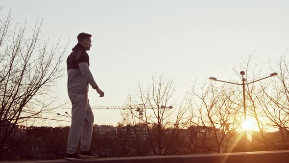 Young and fit man having evening workout outdoor. Urban sunset background.