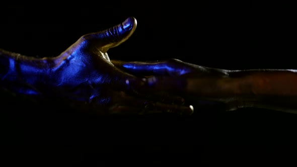 Closeup of Male and Female Hands with Metallic Golden Skin on a Black Background