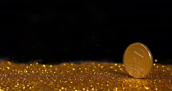 Coin of 1 Euro Rolling on Gold Powder against Black Background, Slow motion 4K