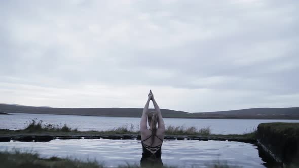 Woman sitting in pool near stones