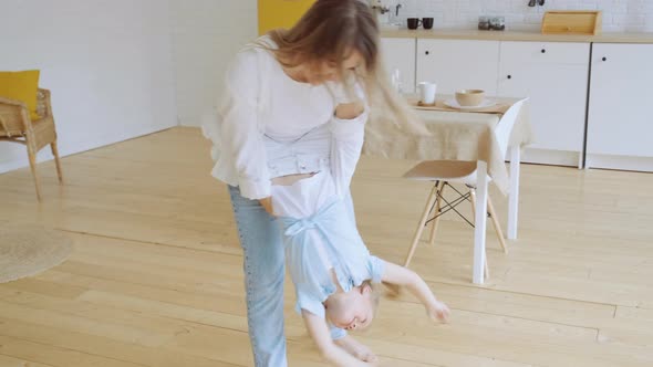 Young Mother Has Fun with Little Daughter Holding Her and Dancing Tossing Kid