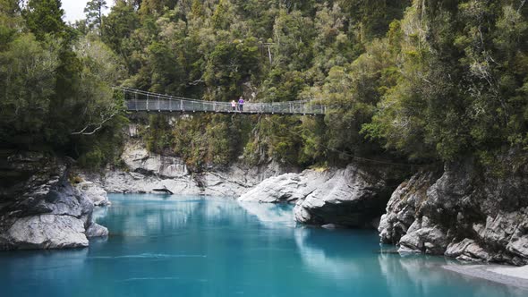 tourists admire the beautiful hokitika gorge from the swing bridge