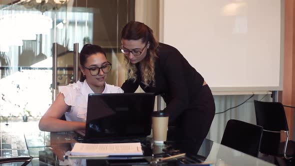 Two Business Women Discuss a Business Project in the Office Using a Computer with a Good Mood