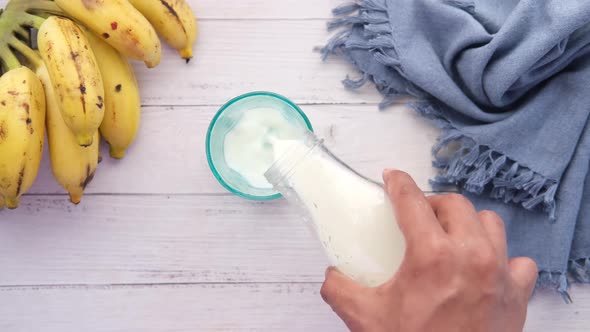 Pouring Milk Into a Glass and Banana on Table