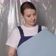 Woman Builder in Blue Overalls with Roll of Blue Wallpaper - VideoHive Item for Sale