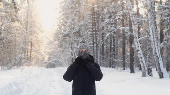 teenager in winter knitted hat and  scarf walks through the winter snow forest.