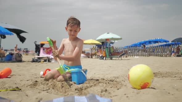 On a Hot Hot Summer Day a Boy is Playing with Sand and Toys