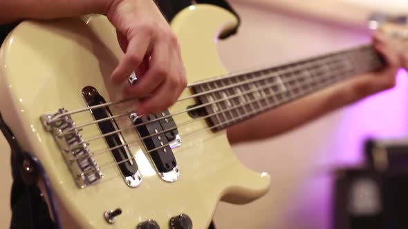 Close-up of Male Bassist Hands Playing on Electric Bass Guitar Touching Strings on Rehearsal